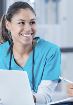 Picture of student in scrubs sitting by a computer